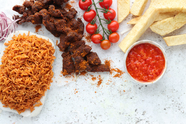 Jollof Rice and Beef Suya from Afrisian paired with vibrant cherry tomatoes and a red sauce.