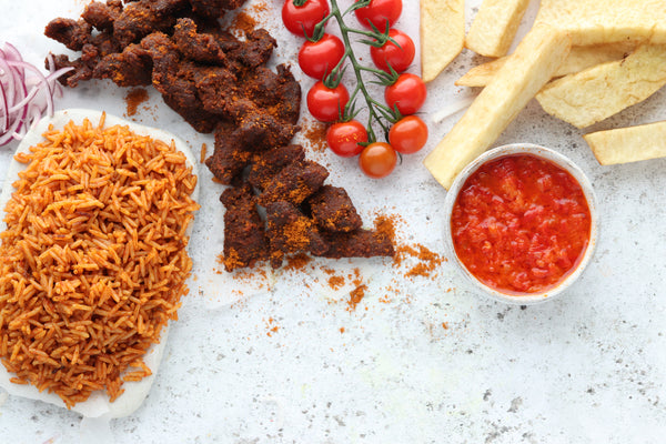 Jollof Rice and Beef Suya from Afrisian paired with vibrant cherry tomatoes and a red sauce.  